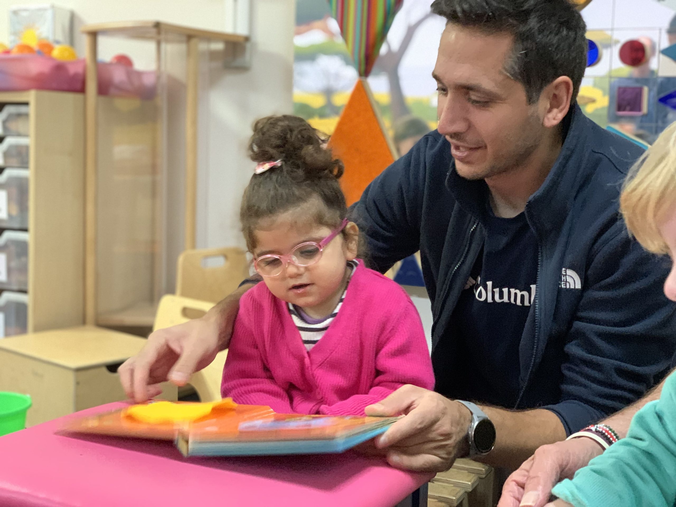 A dad reading with his daughter in a conductive education session.