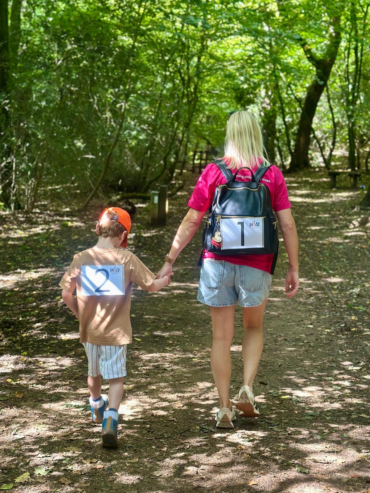 A mother and son walking in the woods.